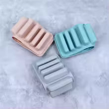 Three ribbed silicone bands in pink, gray, and teal on a light gray background